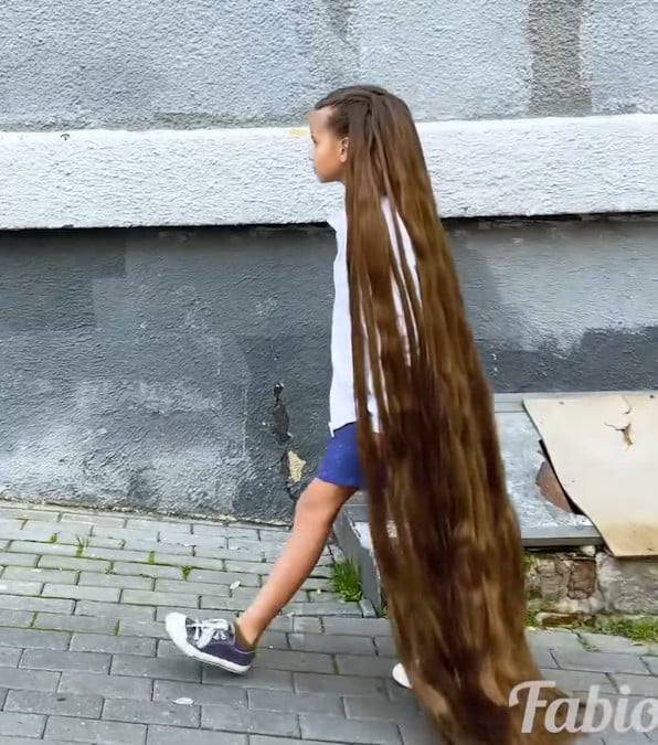 bambina taglia i sui lunghi capelli per aiutare un cane